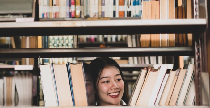 Young Asian women are searching for books and reading books on the tables and aisles of the college